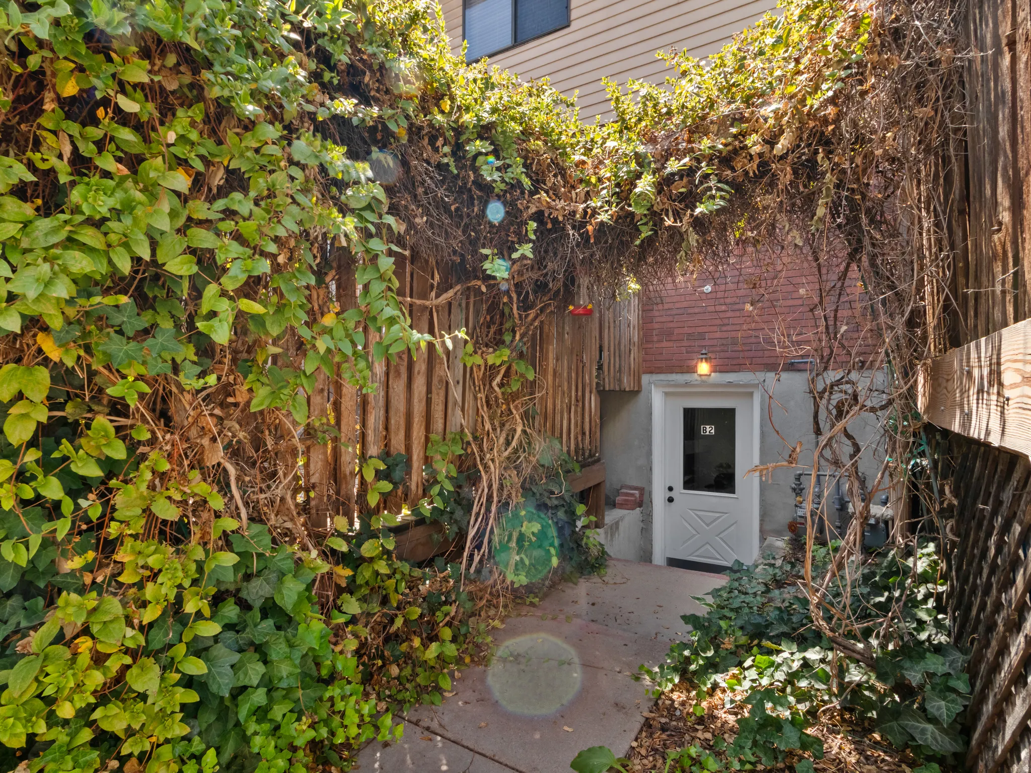 Private entryway featuring a white paneled door with a transom window, brick facade, and a dedicated exterior light fixture