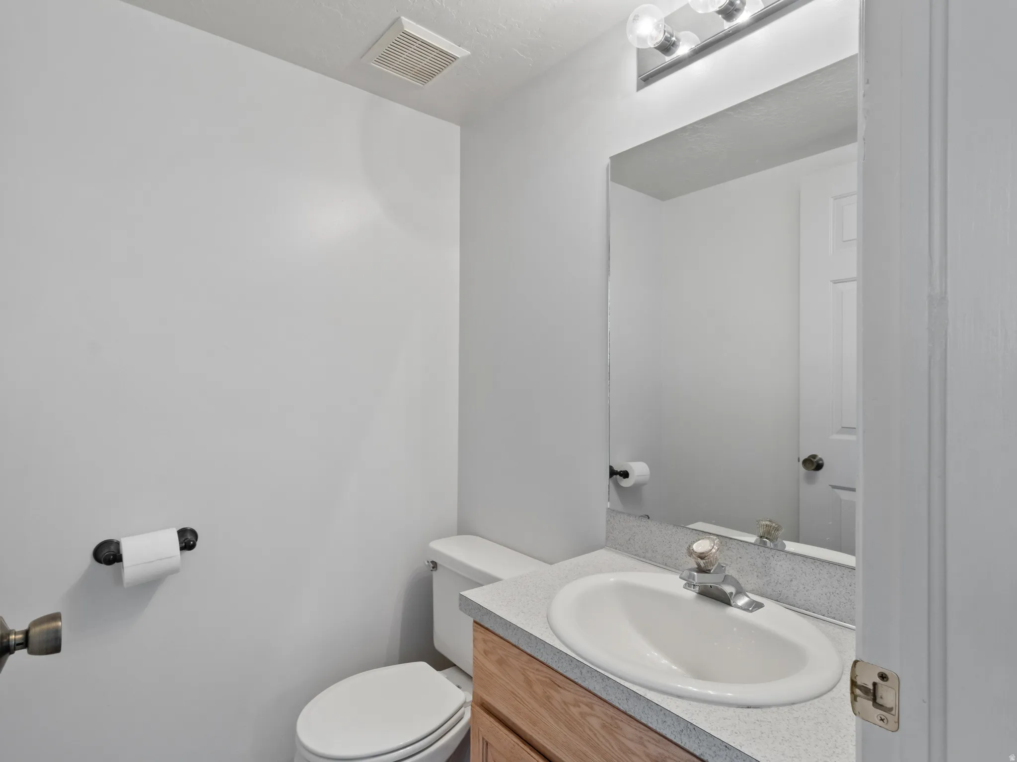 Bathroom featuring a built-in vanity with wood-finish cabinetry, a white oval sink, and a speckled countertop