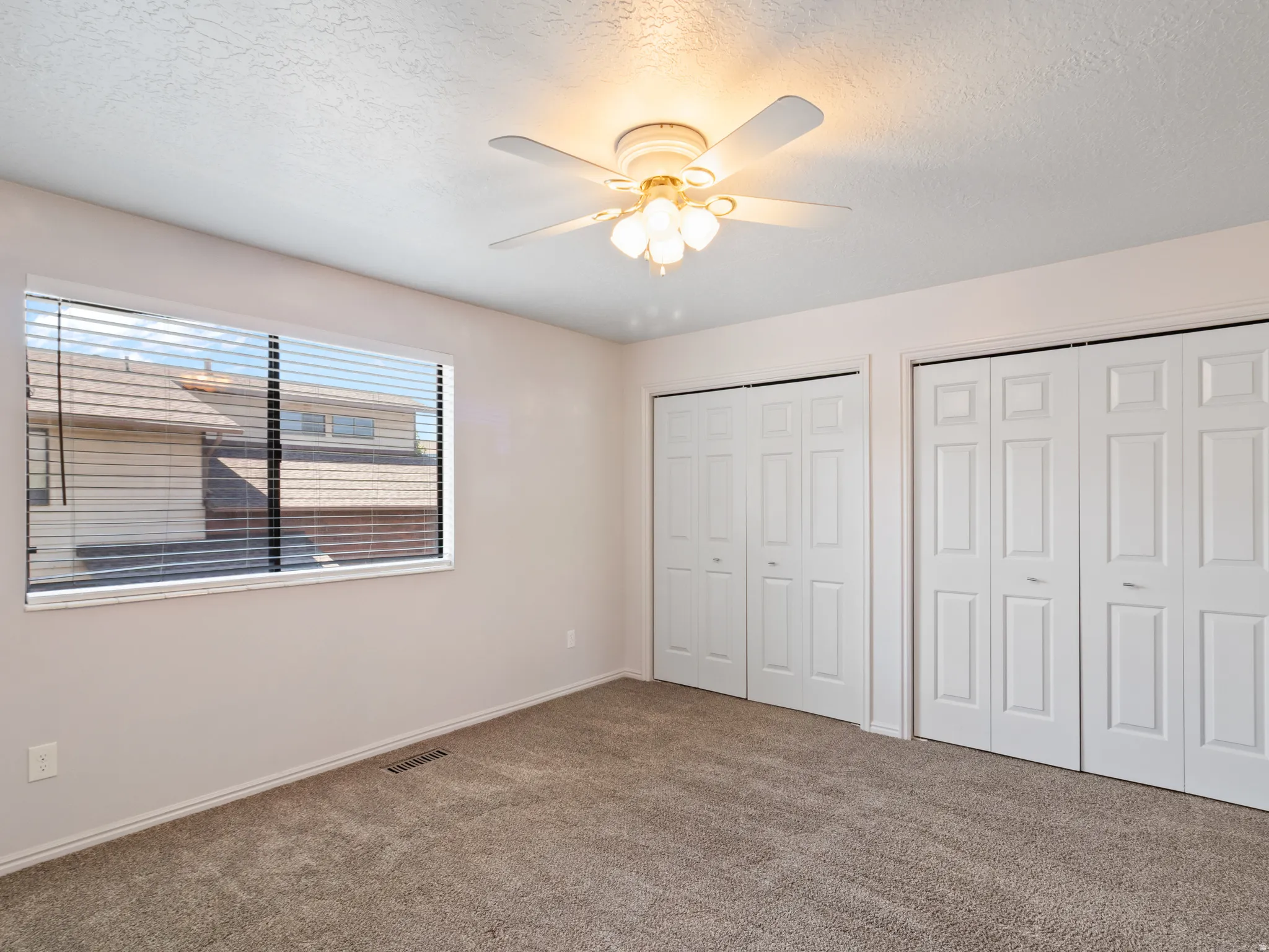 Room with neutral-toned walls, textured ceiling, and carpeting