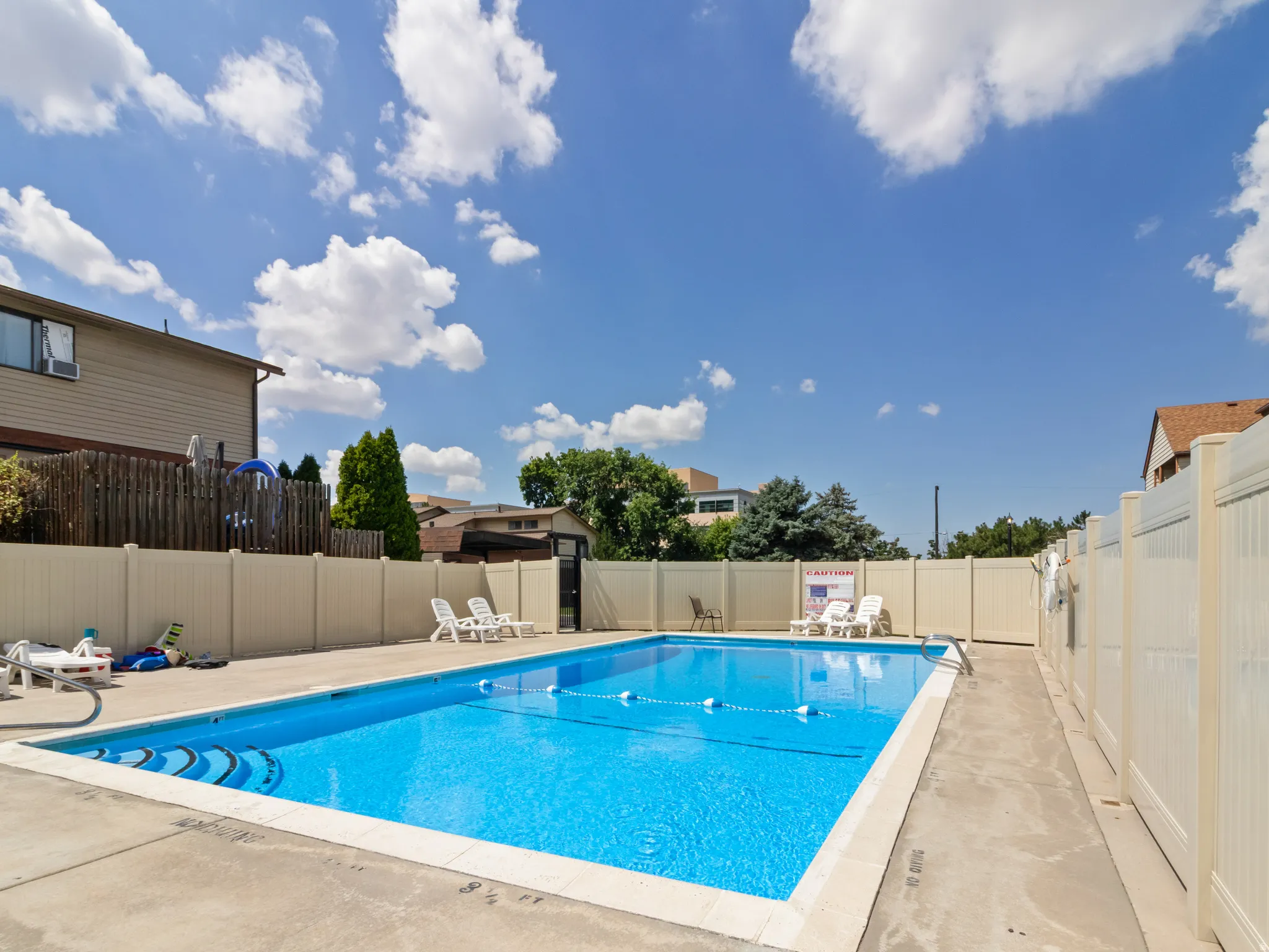 Outdoor swimming pool with concrete decking, a perimeter fence, and direct access gate