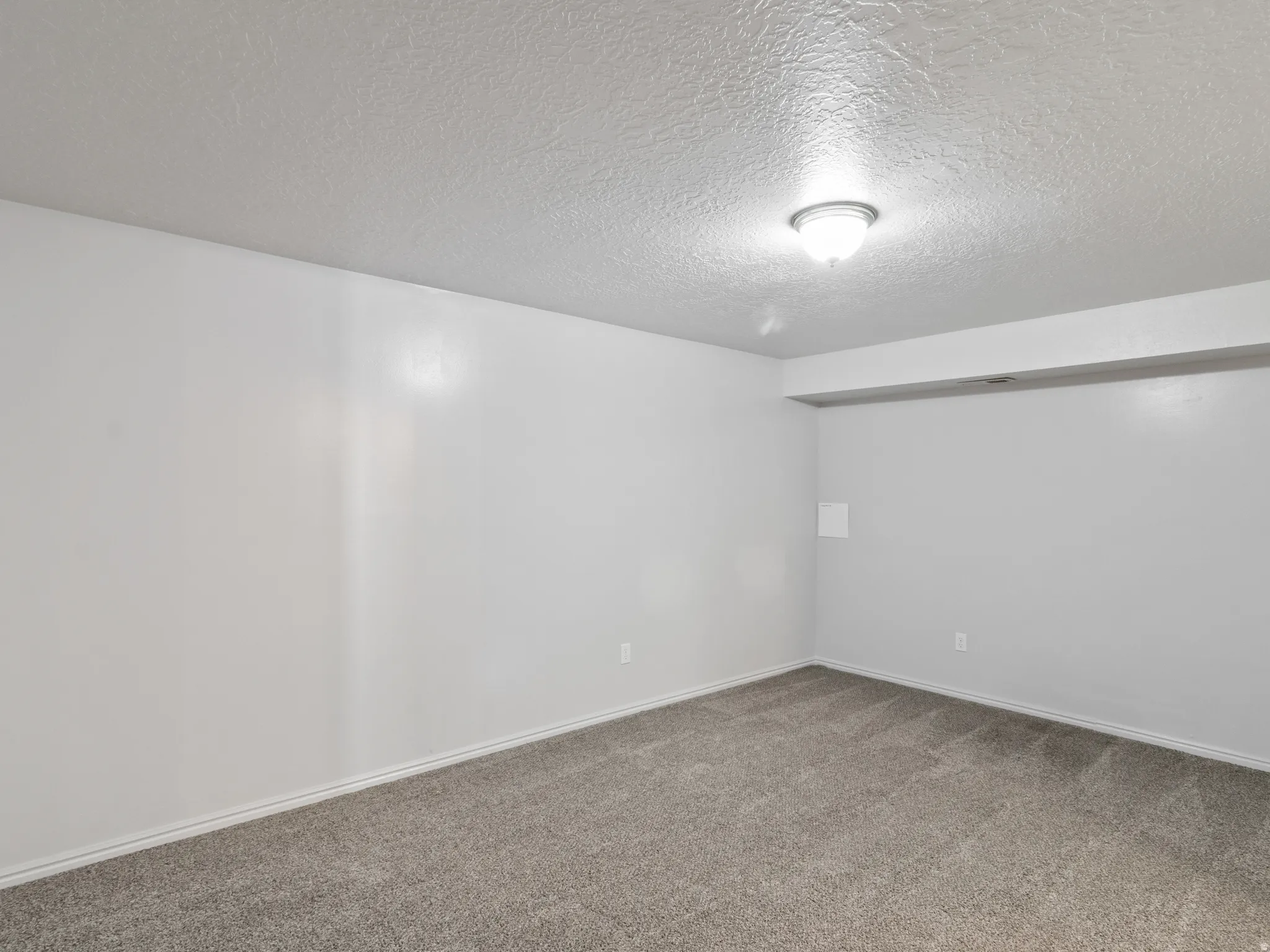 Room featuring light gray walls, gray carpet flooring, white baseboards, and a semi-flush mount ceiling light
