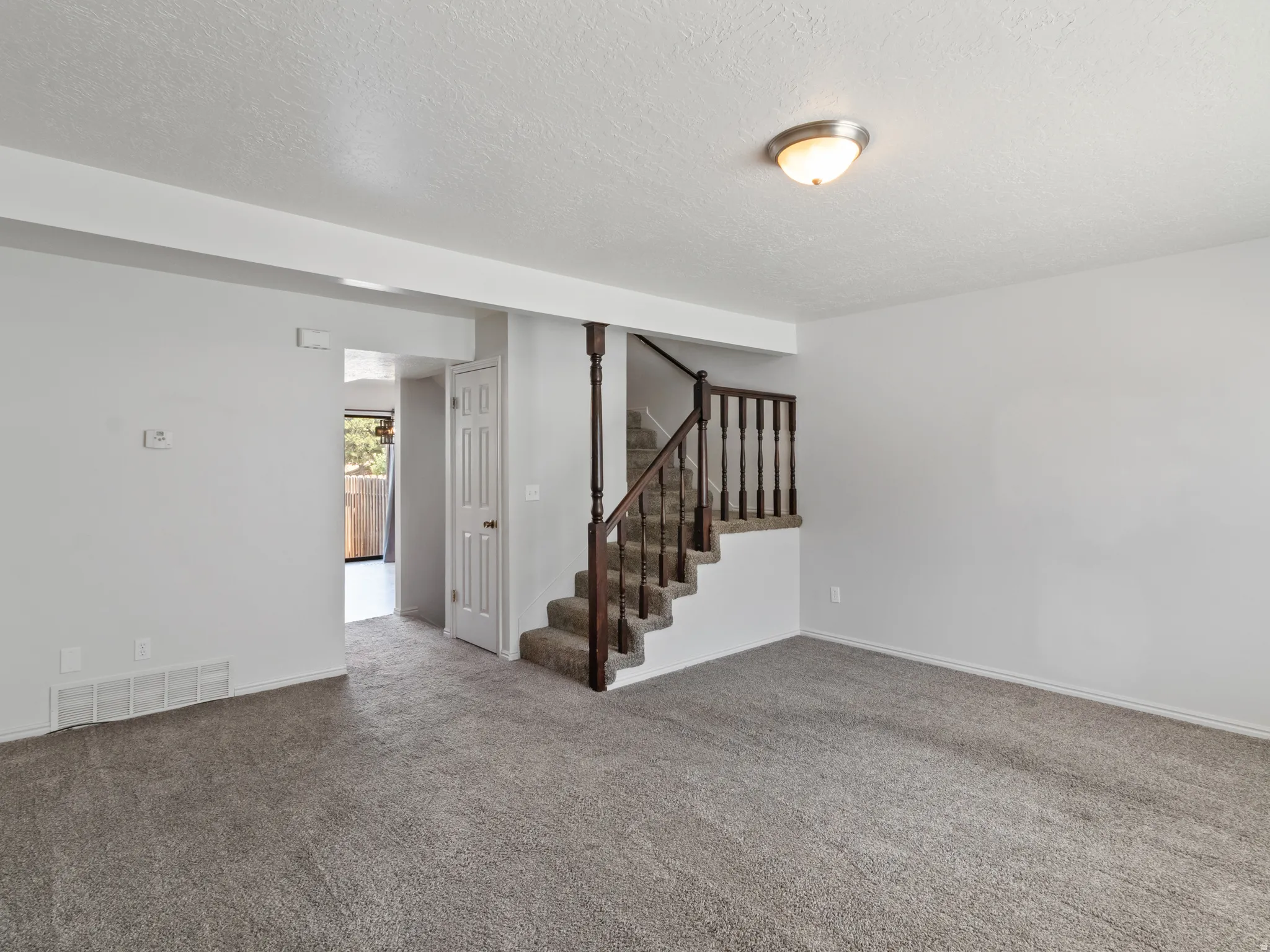 Carpeted living area with light-toned walls and a ceiling-mounted light fixture