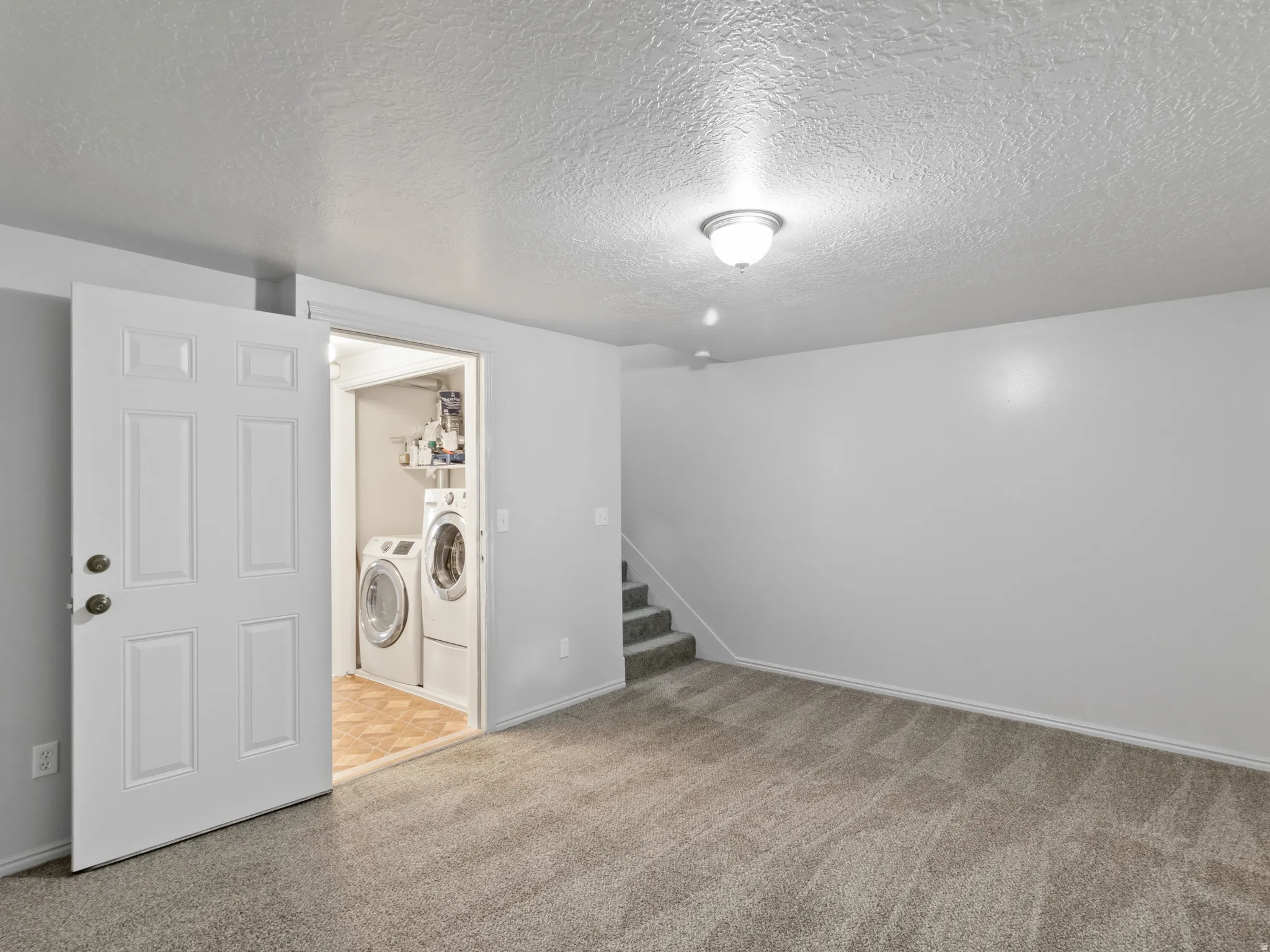 Carpeted room with a laundry area featuring a washer and dryer, light gray walls, and a recessed ceiling light fixture
