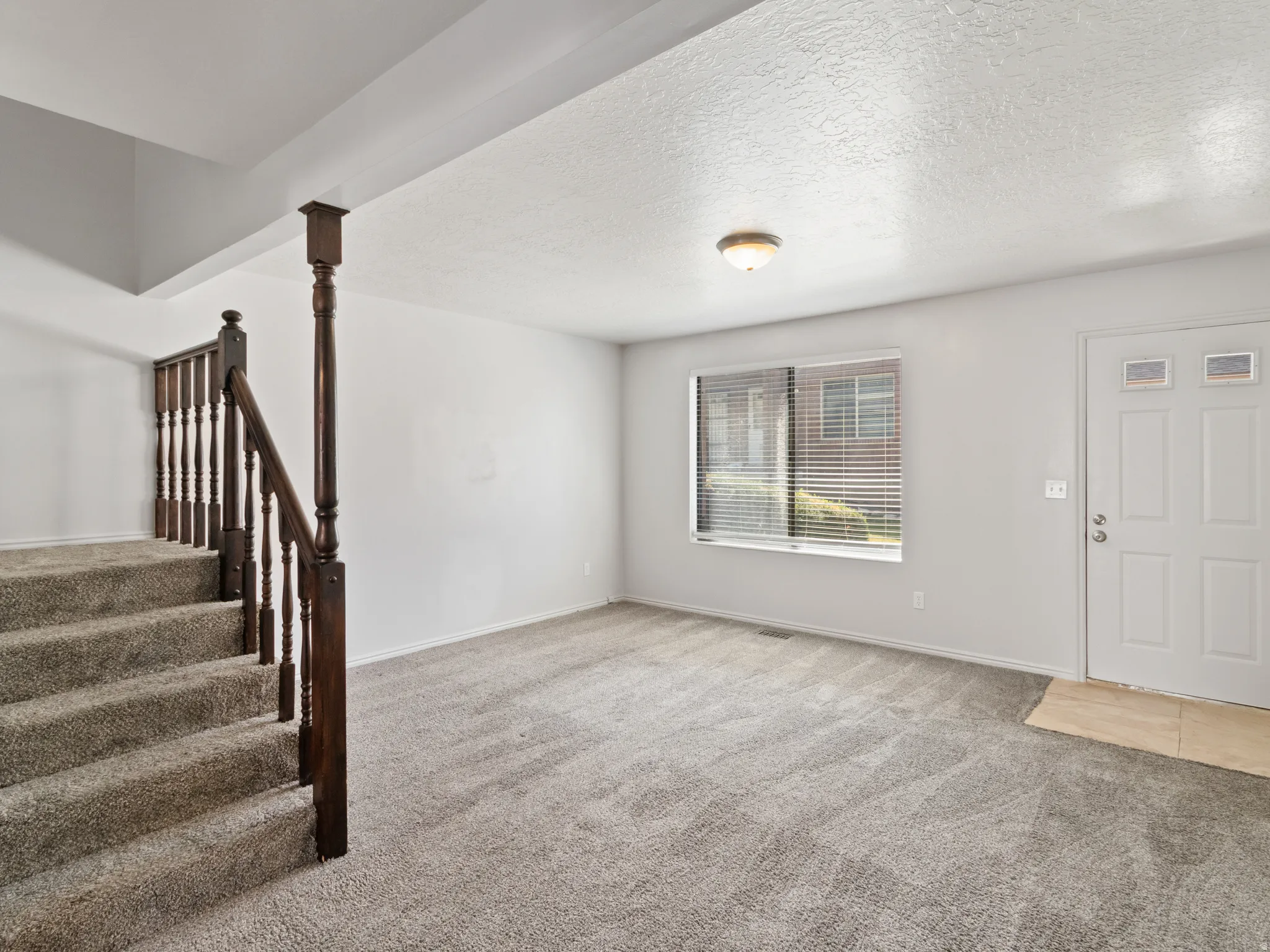 Entry area featuring neutral carpeting, a white paneled front door with decorative lites, and a rectangular window with blinds