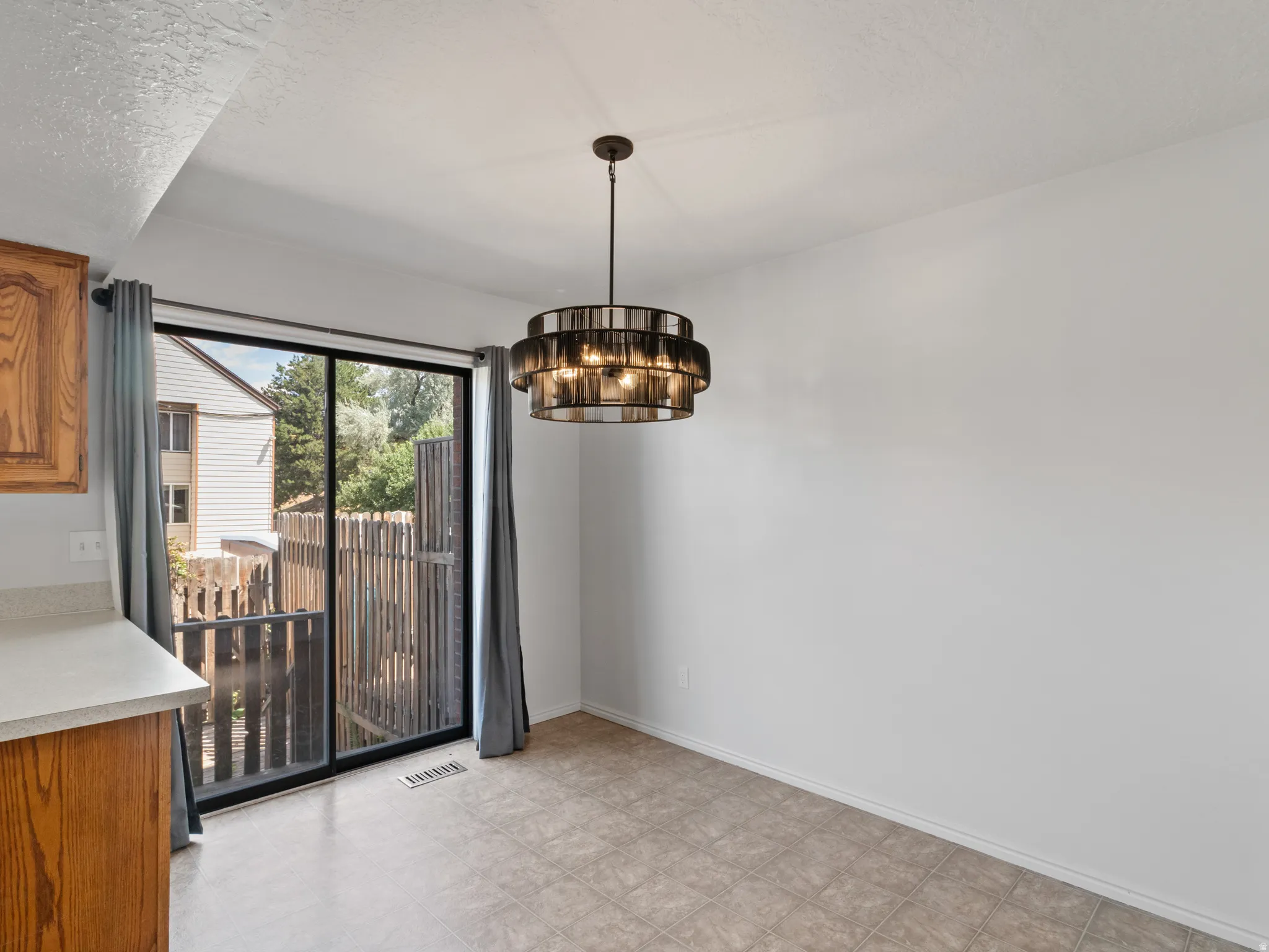 Dining area featuring a contemporary tiered chandelier, sliding glass door, and neutral tile flooring