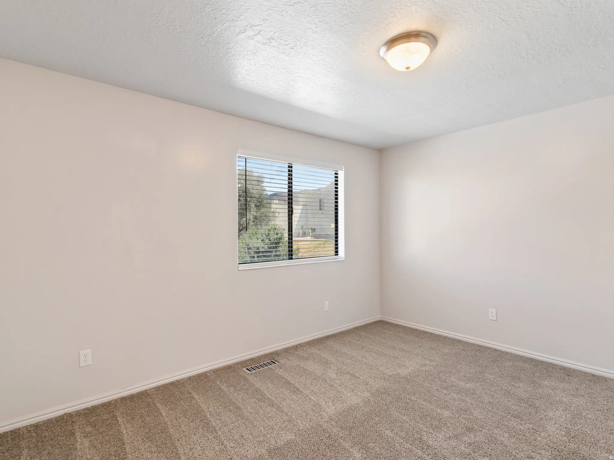 Neutral-toned interior featuring wall-to-wall carpeting and a single window with blinds