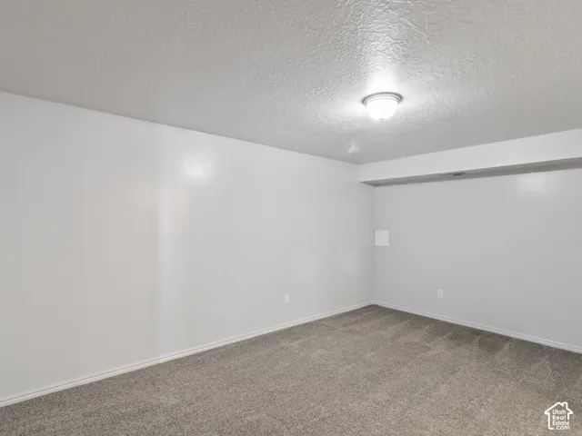 Room featuring light gray walls, gray carpet flooring, white baseboards, and a semi-flush mount ceiling light