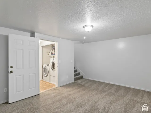 Carpeted room with a laundry area featuring a washer and dryer, light gray walls, and a recessed ceiling light fixture