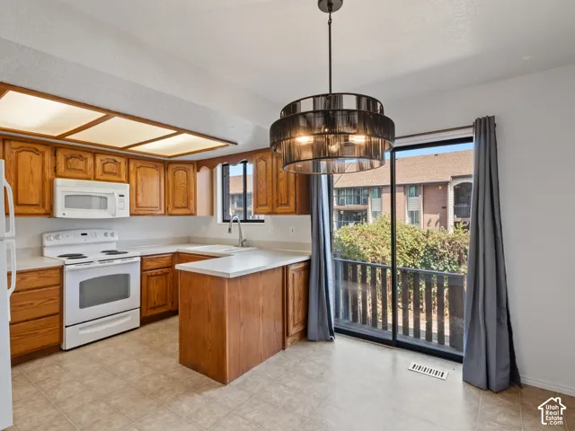 Kitchen with wood cabinetry, white appliances, and light-colored countertops