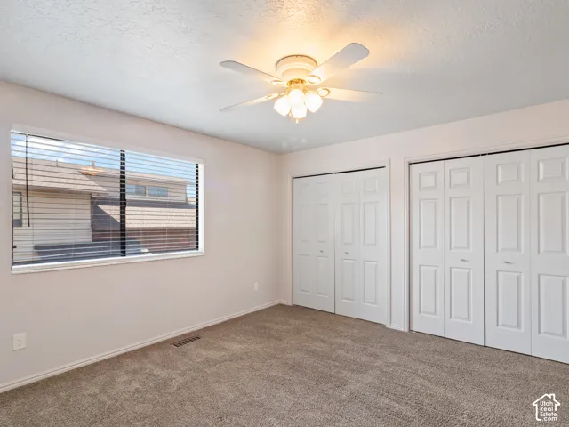 Room with neutral-toned walls, textured ceiling, and carpeting