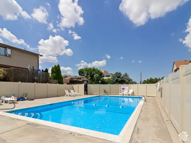 Outdoor swimming pool with concrete decking, a perimeter fence, and direct access gate
