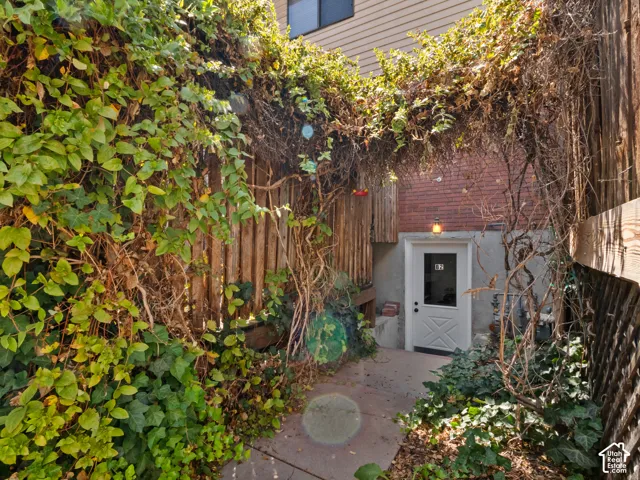 Private entryway featuring a white paneled door with a transom window, brick facade, and a dedicated exterior light fixture