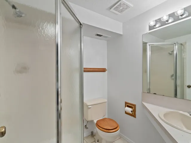 Bathroom featuring a shower stall with clear glass doors, a vanity with an integrated sink, a wall-mounted mirror, and overhead vanity lighting