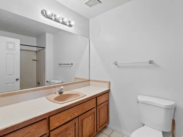 Bathroom featuring a vanity with wood-finish cabinetry, a tiled countertop, and an integrated sink basin