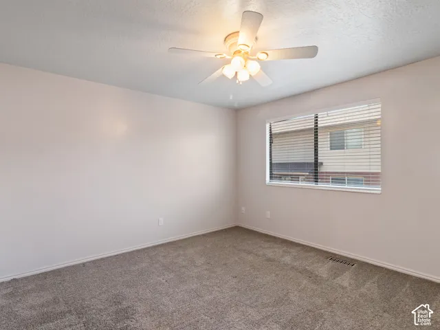 Carpeted room featuring a ceiling fan with integrated lighting, a window with horizontal blinds, and neutral wall tones
