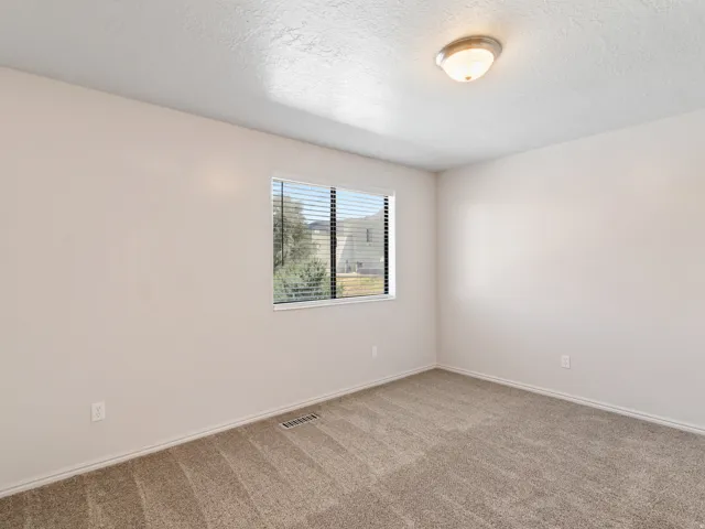 Neutral-toned interior featuring wall-to-wall carpeting and a single window with blinds