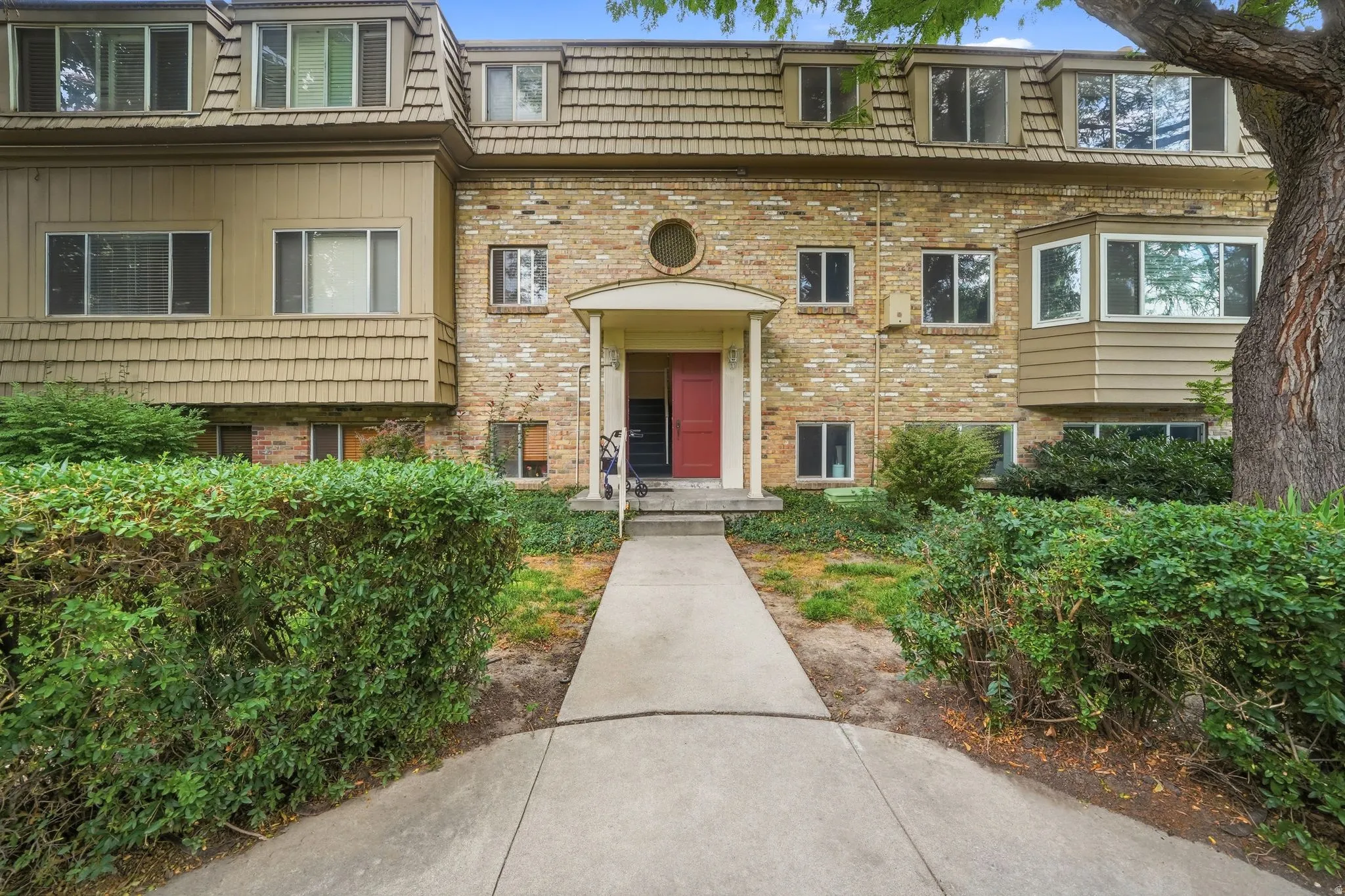 Multi-level building with a red entry door under a covered porch