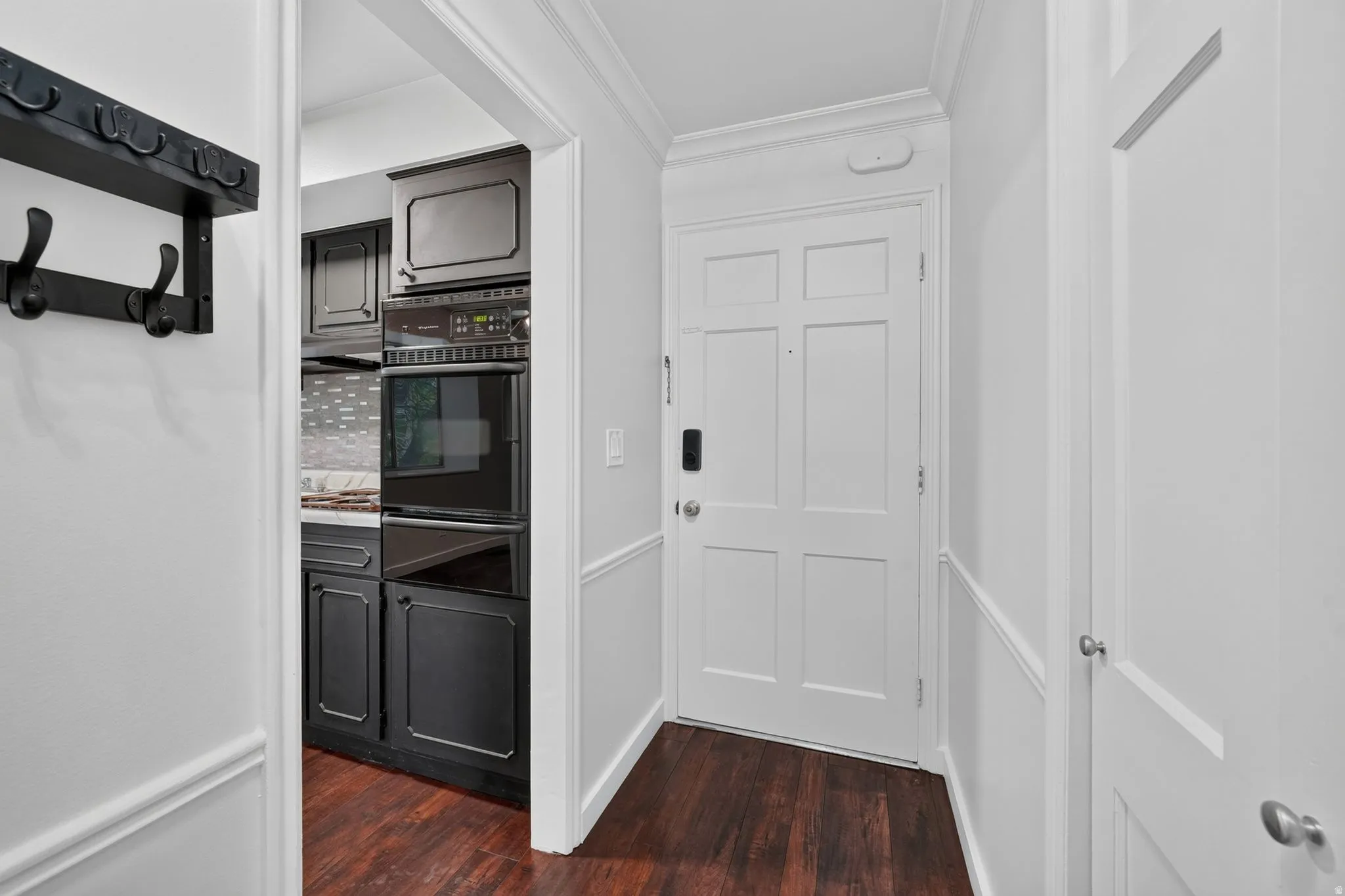 Entryway featuring wood-finish flooring, white panel doors, and wainscoting