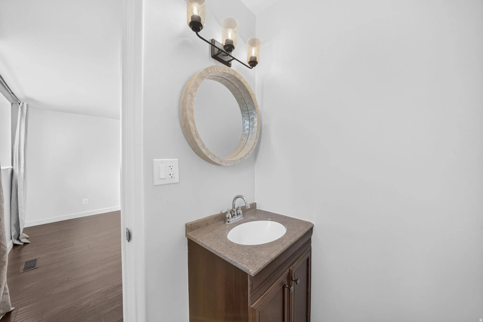 Bathroom vanity featuring a dark wood-finish cabinet with double doors, an integrated white sink, and a light-toned countertop