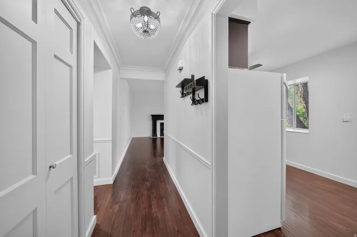 Hallway with wood-finish flooring and crown molding