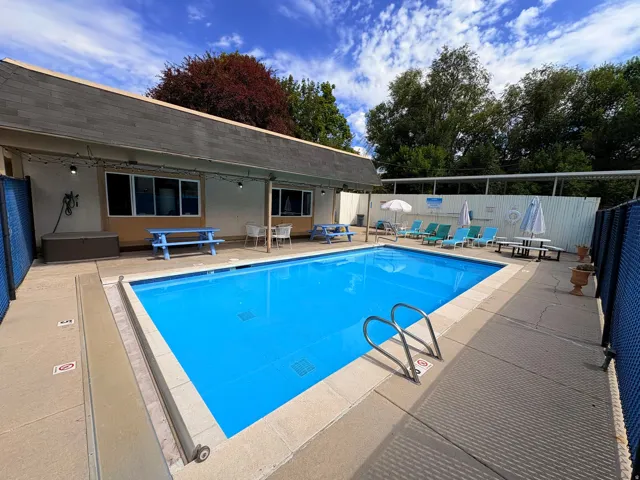 Outdoor swimming pool with a concrete surround, enclosed by blue fencing