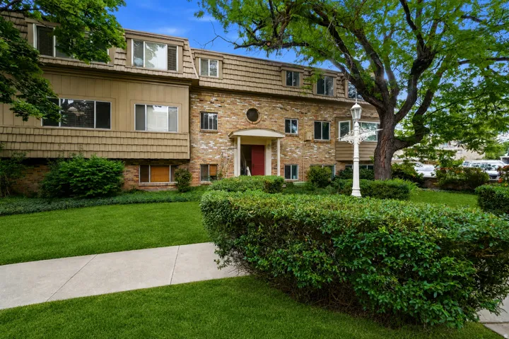 Charming brick and stone exterior with mature shade trees and lush landscaping