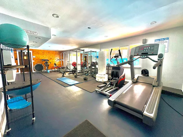 Dedicated fitness room featuring blue rubber flooring, recessed lighting, and a prominent wood-paneled accent wall