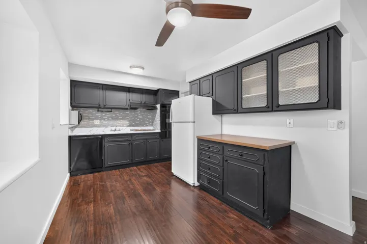 Kitchen featuring dark cabinetry, wood-finish flooring, white countertops, and a tile backsplash