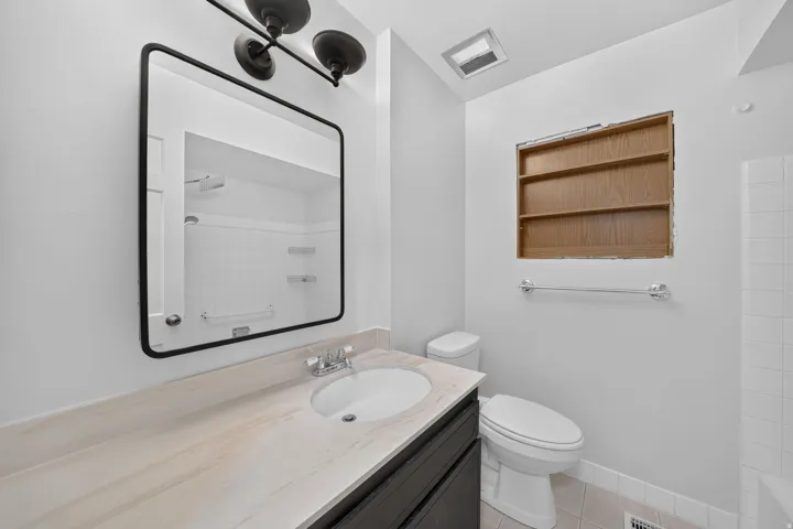 Bathroom featuring a dark wood-finish vanity, a rectangular undermount sink, and a light-toned countertop