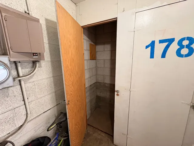 Storage unit featuring concrete block walls, a wooden entry door, and painted white access doors