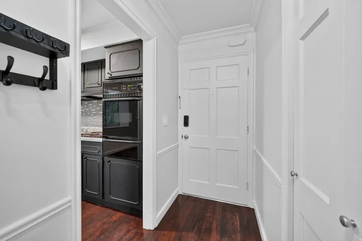 Entryway featuring wood-finish flooring, white panel doors, and wainscoting