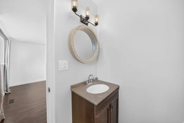 Bathroom vanity featuring a dark wood-finish cabinet with double doors, an integrated white sink, and a light-toned countertop