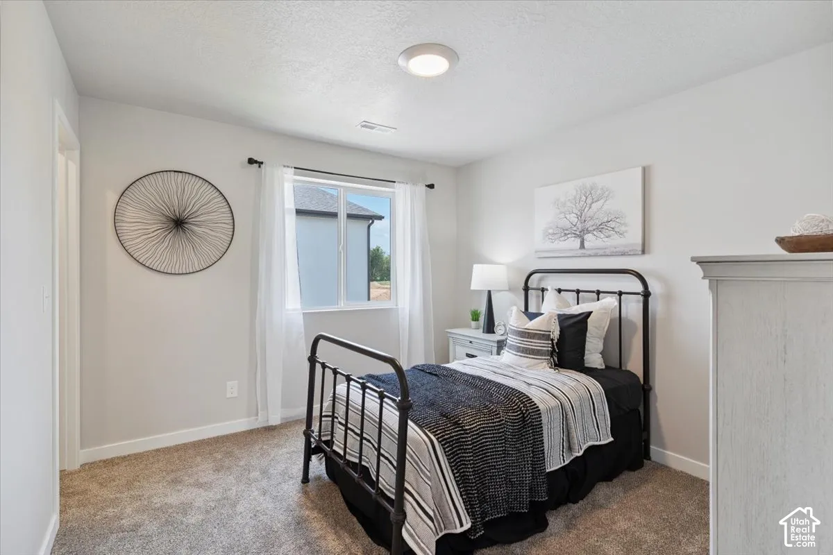 Bedroom featuring light gray walls, a window with white sheers, a flush-mount ceiling light, and carpet flooring