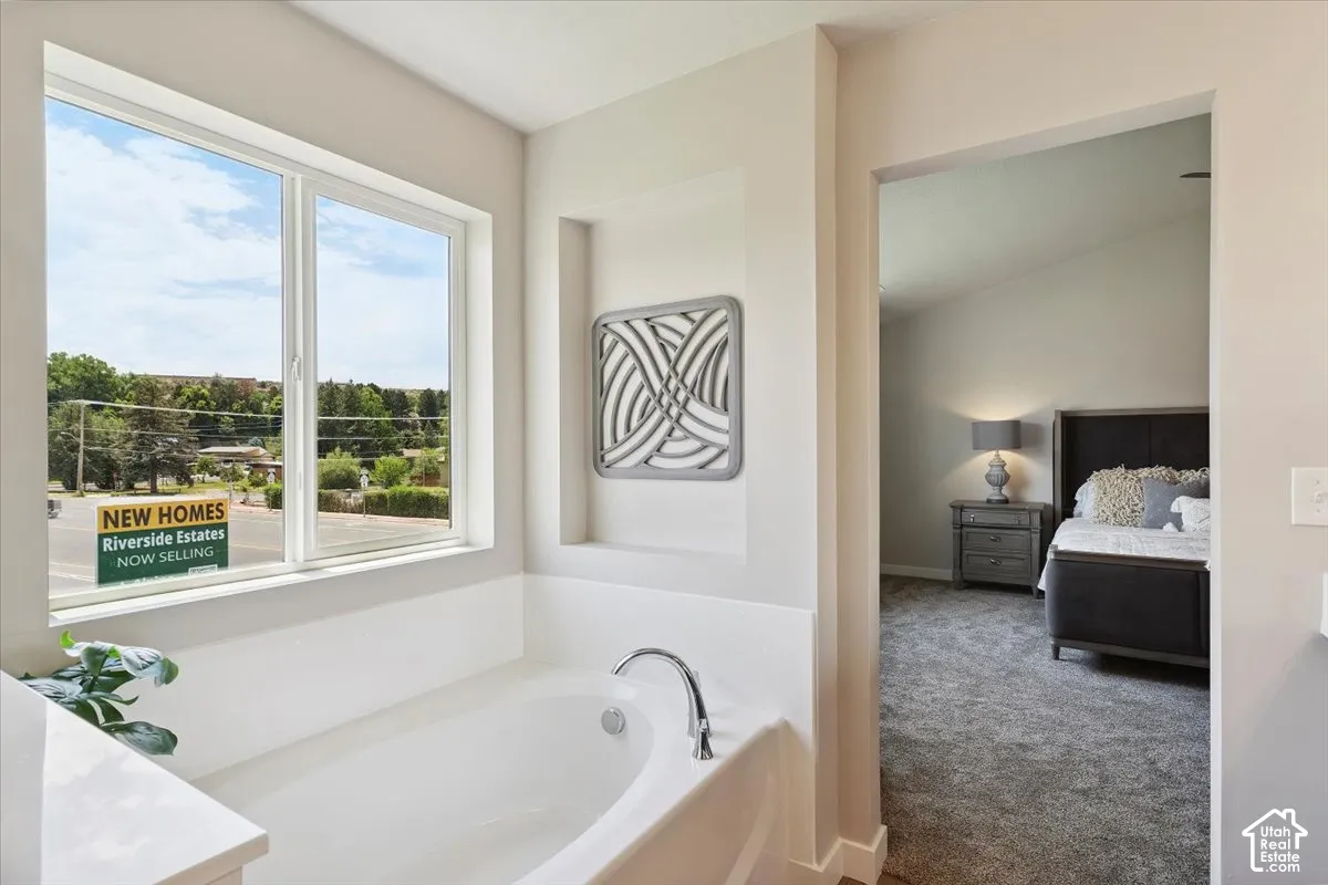 Primary bathroom featuring soaking tub with chrome fixtures and an adjacent window