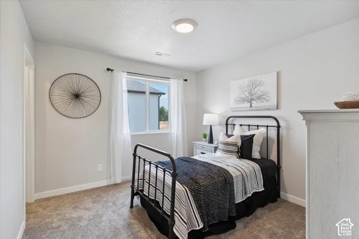 Bedroom featuring light gray walls, a window with white sheers, a flush-mount ceiling light, and carpet flooring