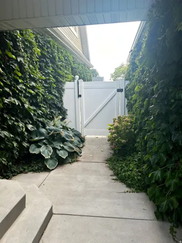Concrete walkway leading to a white privacy fence and gate