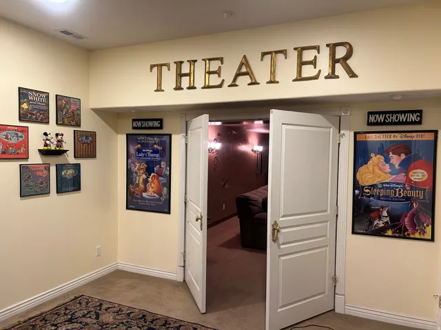 Dedicated home theater entrance with double white paneled doors and brass hardware