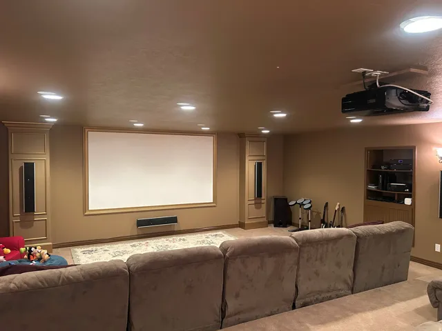 Dedicated media room featuring a large projection screen with ornate wood trim and integrated speakers