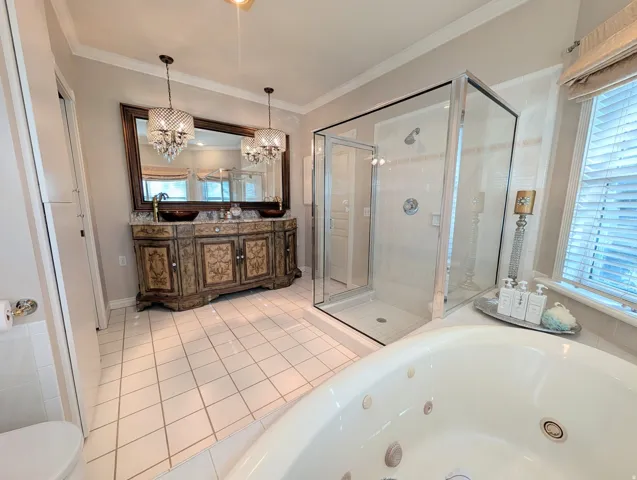 Bathroom featuring a jetted soaking tub, walk-in glass shower, and a dual vanity with vessel sinks