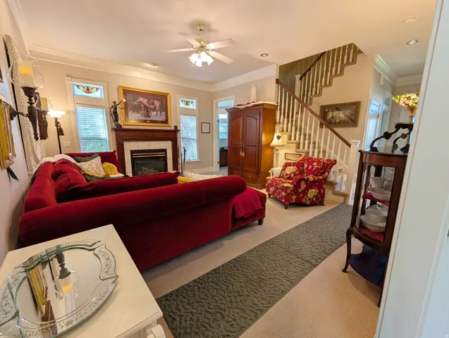 Living area featuring a fireplace with a wood mantel and tile surround, crown molding, and recessed lighting