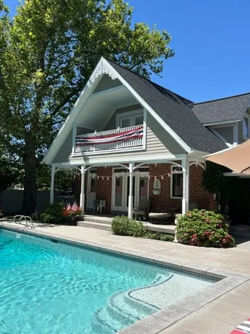 Outdoor swimming pool with integrated steps, surrounded by concrete decking & Bonus Pool House