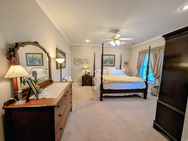 Spacious bedroom featuring neutral wall tones, crown molding, and recessed lighting