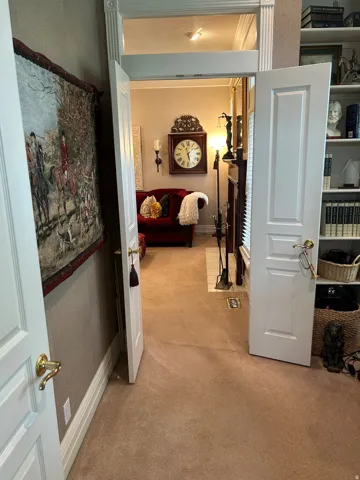 Archway entry to a carpeted room featuring a built-in wall clock