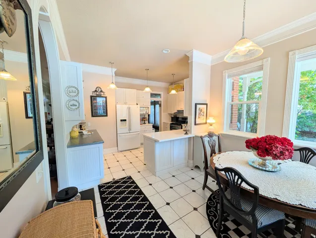 Kitchen and dining area featuring white cabinetry, a central island, and black and white floor tiling