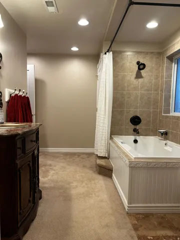 Bathroom featuring a built-in tub with beadboard paneling, tile surround, and a dark bronze shower fixture