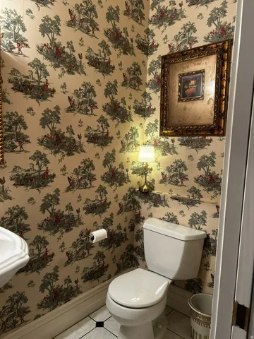 Powder room featuring toile wallpaper, wainscoting, and a pedestal sink