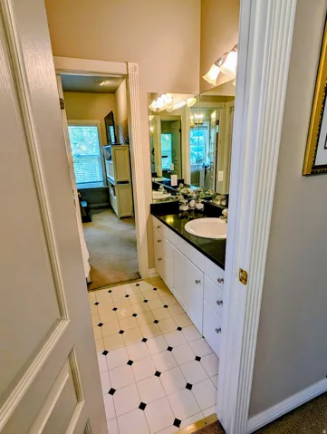 Vanity area featuring a single basin sink, dark countertop, and white cabinetry
