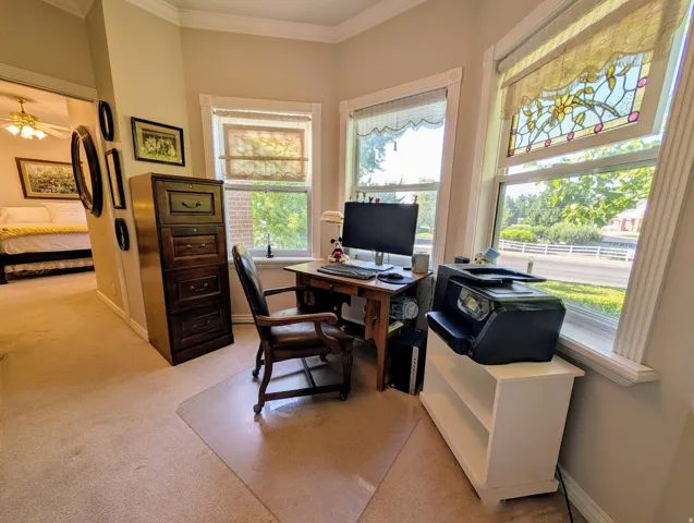 Dedicated corner space featuring multiple windows, detailed crown molding, and a built-in shelving unit