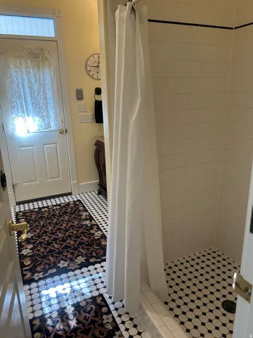 Shower with white subway tile walls and black and white octagonal floor tile