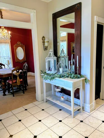 Tiled flooring with black accent squares, recessed wall sconce, crown molding, and decorative doorway trim